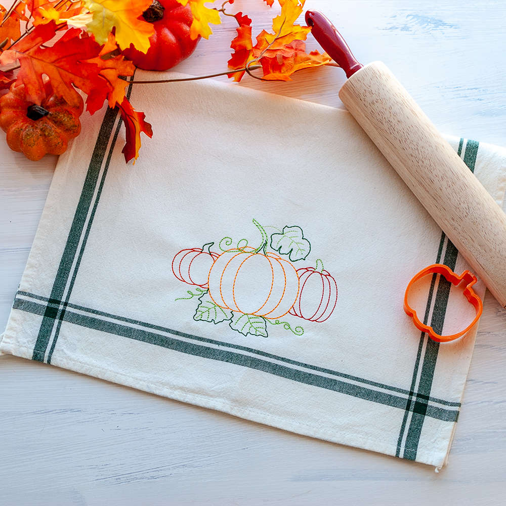 Three pumpkins embroidered on a dish towel