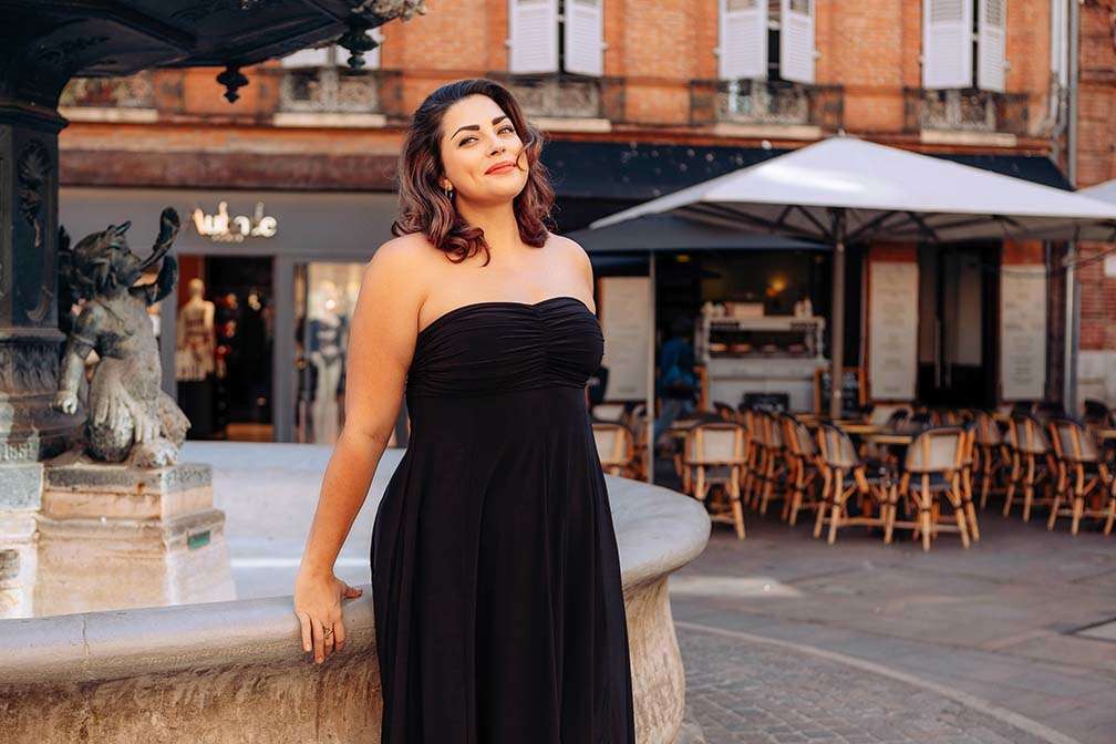 Tegan wearing a Diane Kroe Bubble Dress, leaning on a fountain in Toulouse