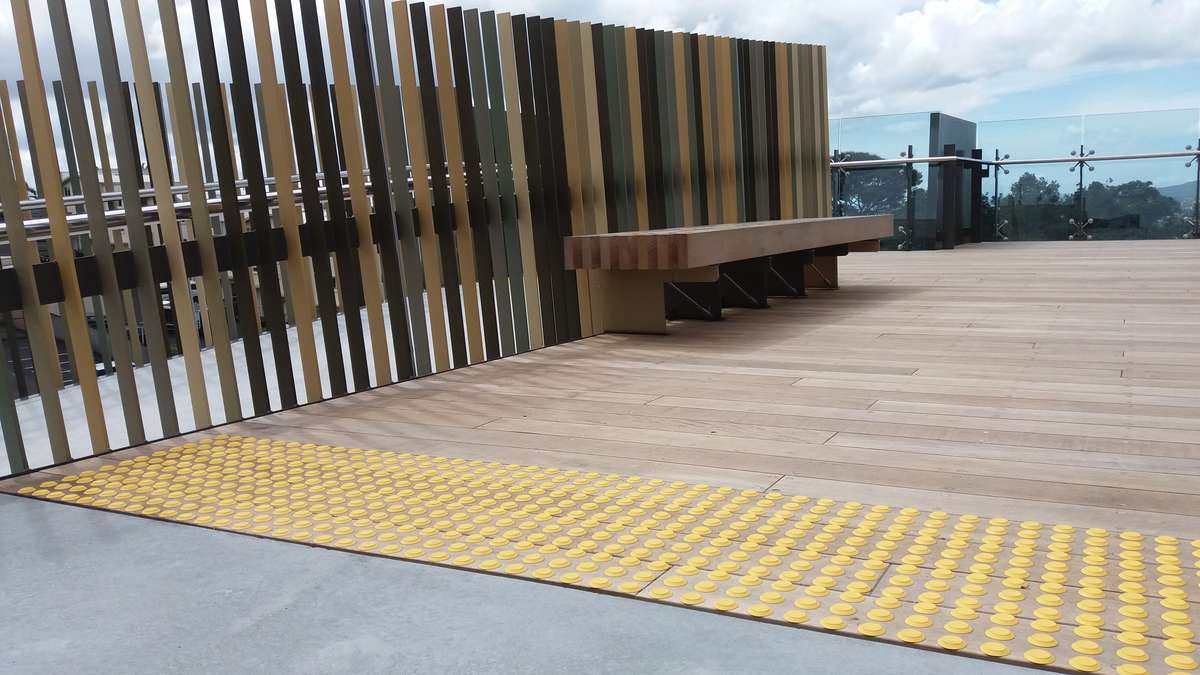 Yellow polyurethane tactile indicators on timber decking