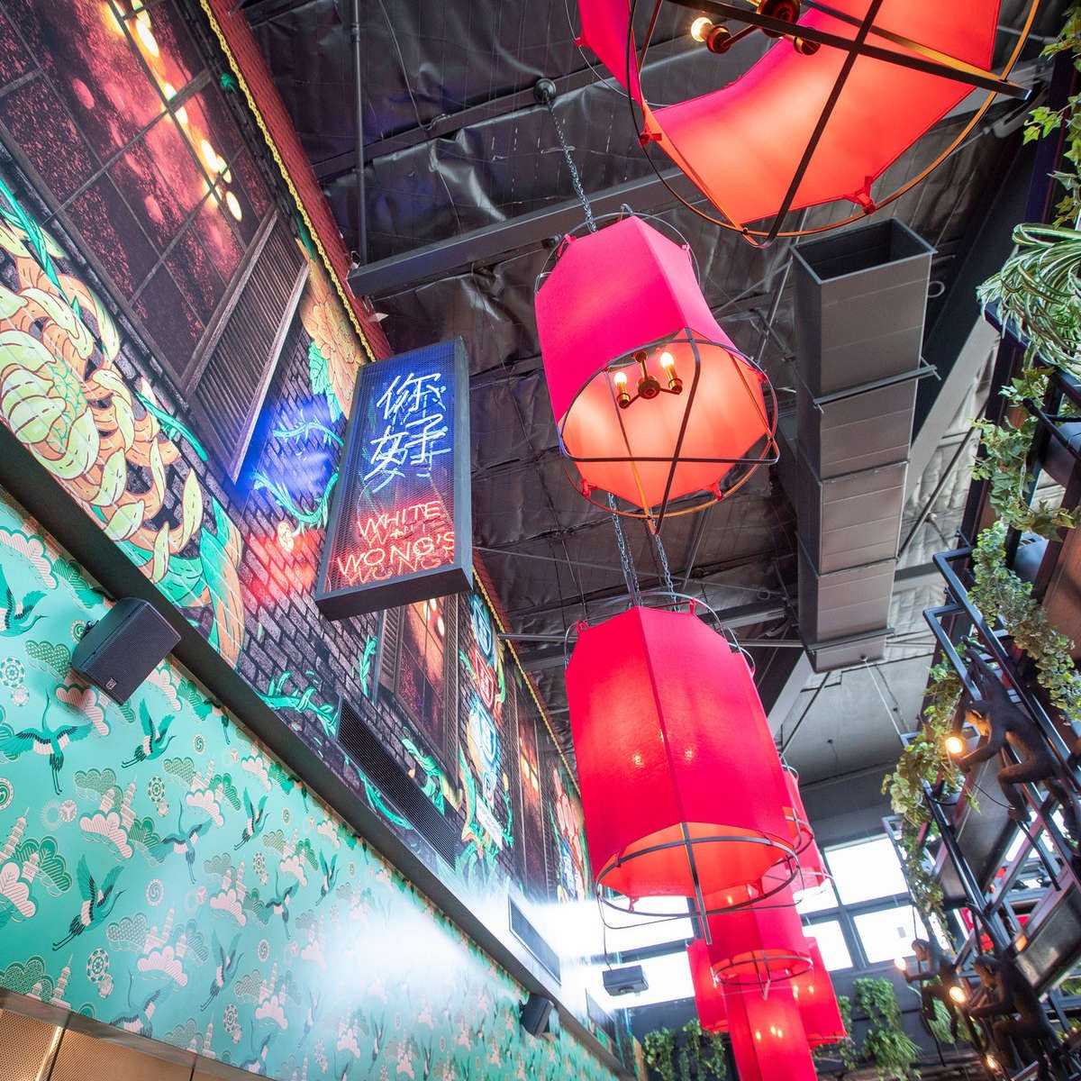 View looking up at lanterns and neon artwork in rooftop dining area