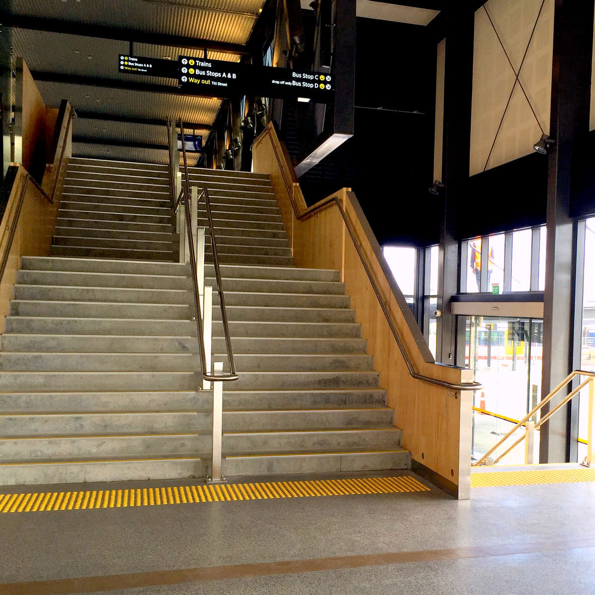 Yellow polyurethane tactile indicators on polished concrete at bottom of stairs