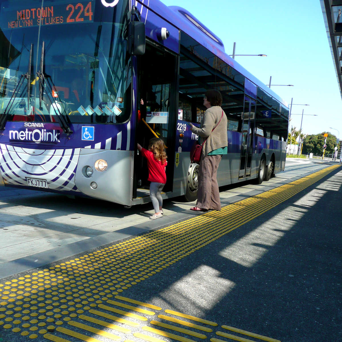 Small child and motherboard bus, walking over TacPro yellow polyurethane warning and directional tactile indicators 