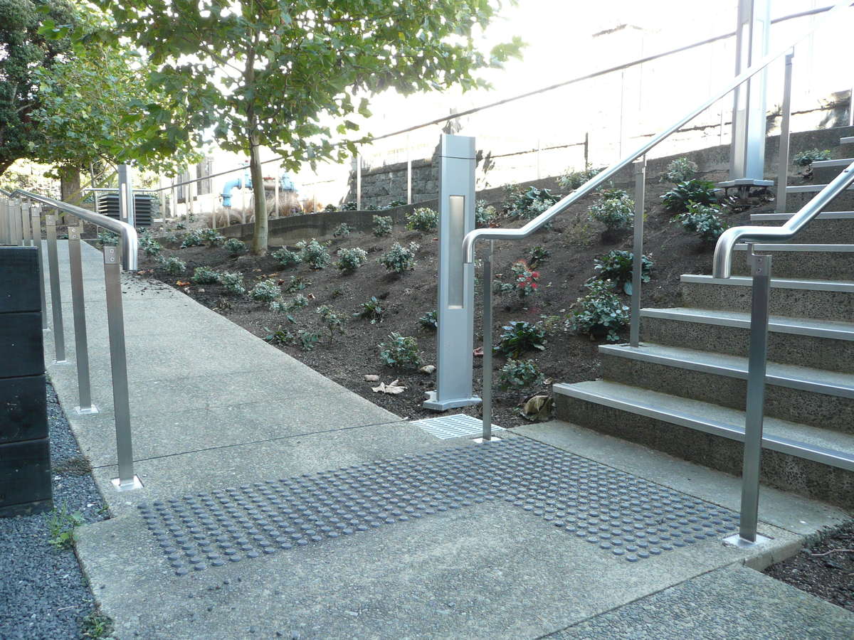 TacPro black polyurethane tactile indicators installed on concrete at junction at bottom of multiple stairs 