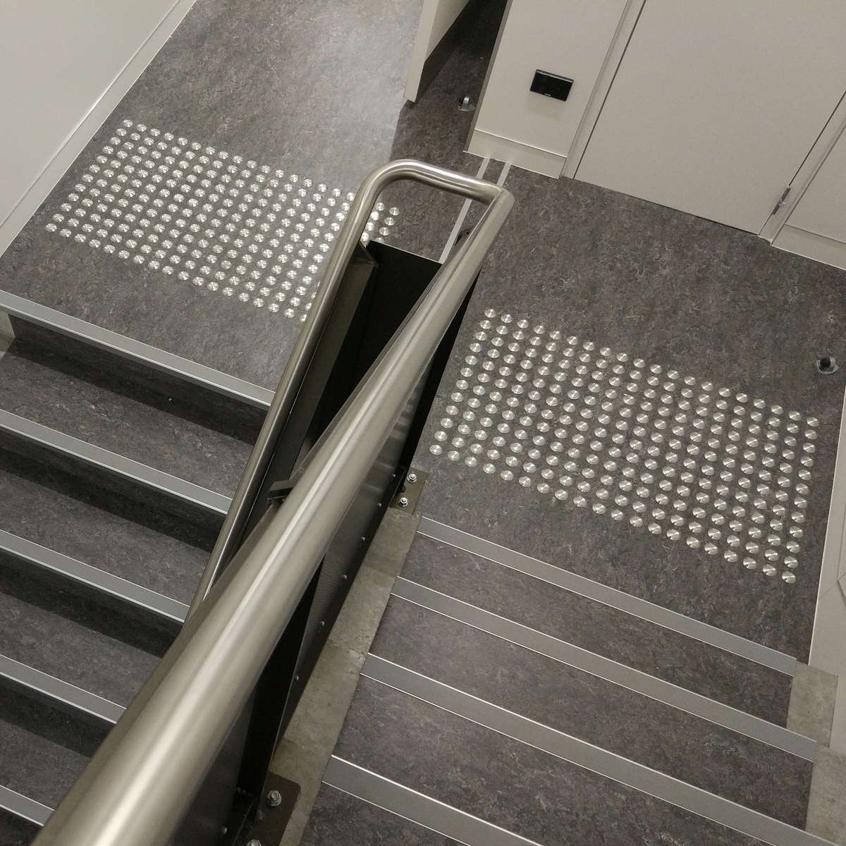 TacPro stainless steel tactile indicators on lino at the top and bottom of stairs