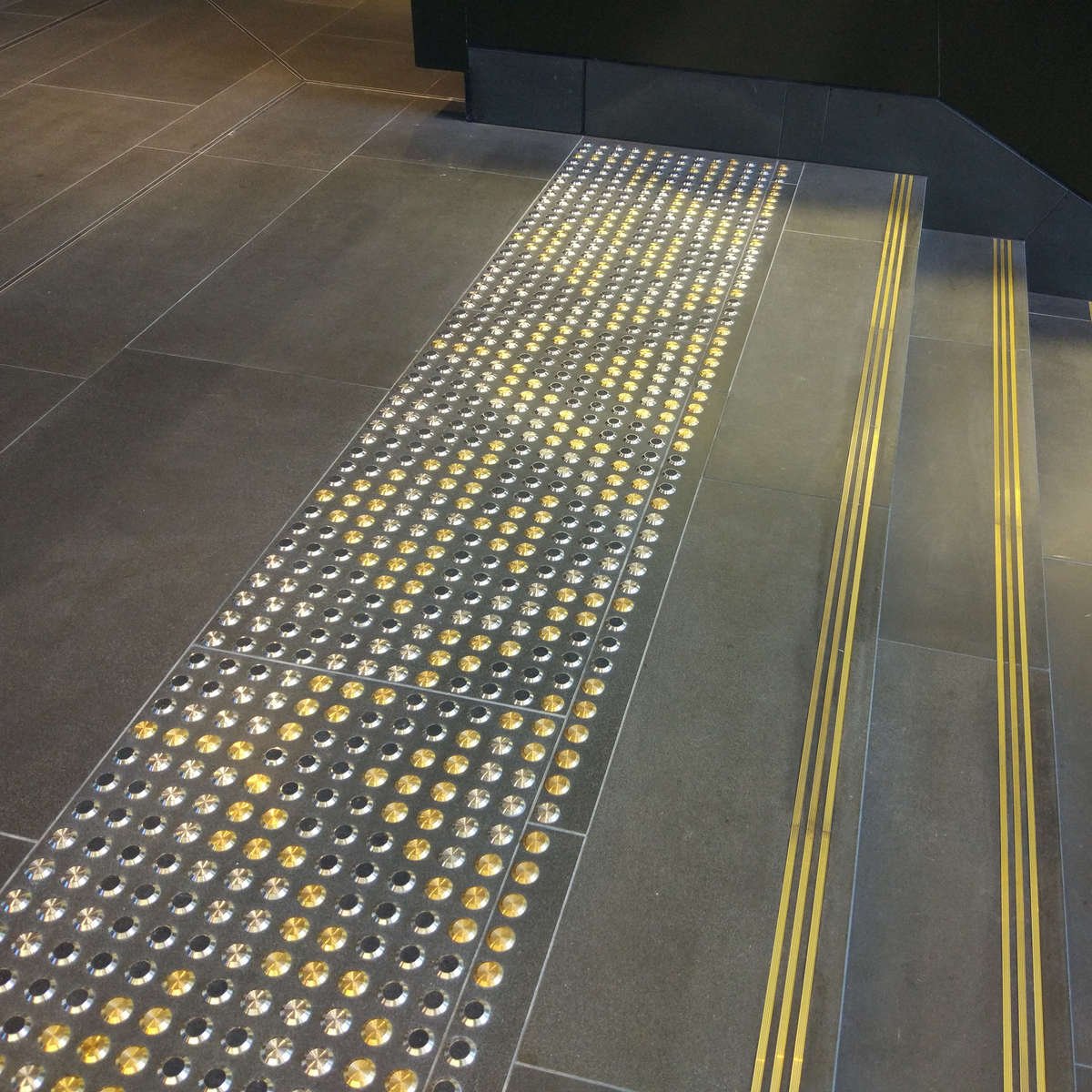 TacPro brass, stainless steel, and stainless steel with black carborundum arranged in a pattern at the top of stairs 