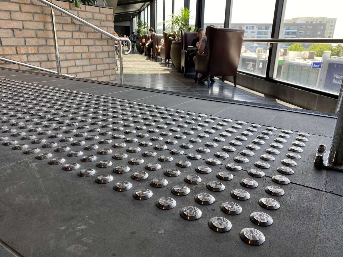 TacPro stainless steel tactile indicators on bluestone at top of stair in food court seating area