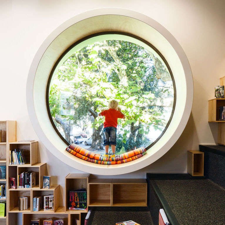 Child looks out circular window in children's play area