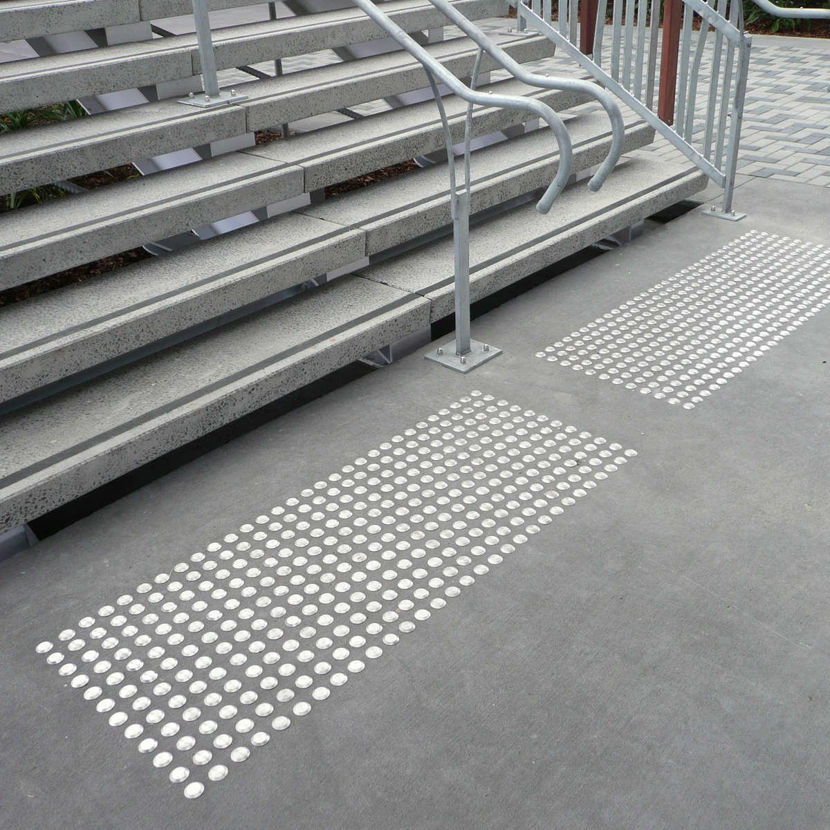 TacPro stainless steel tactile indicators on concrete at the bottom of stairs