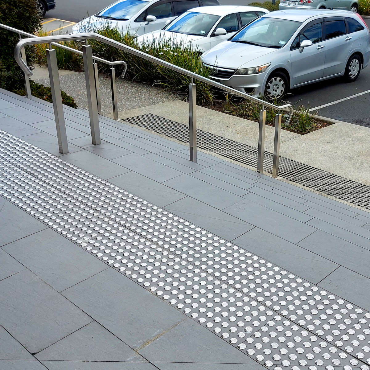 TacPro stainless steel (top) and black polyurethane (bottom) tactile indicators installed at stairs.