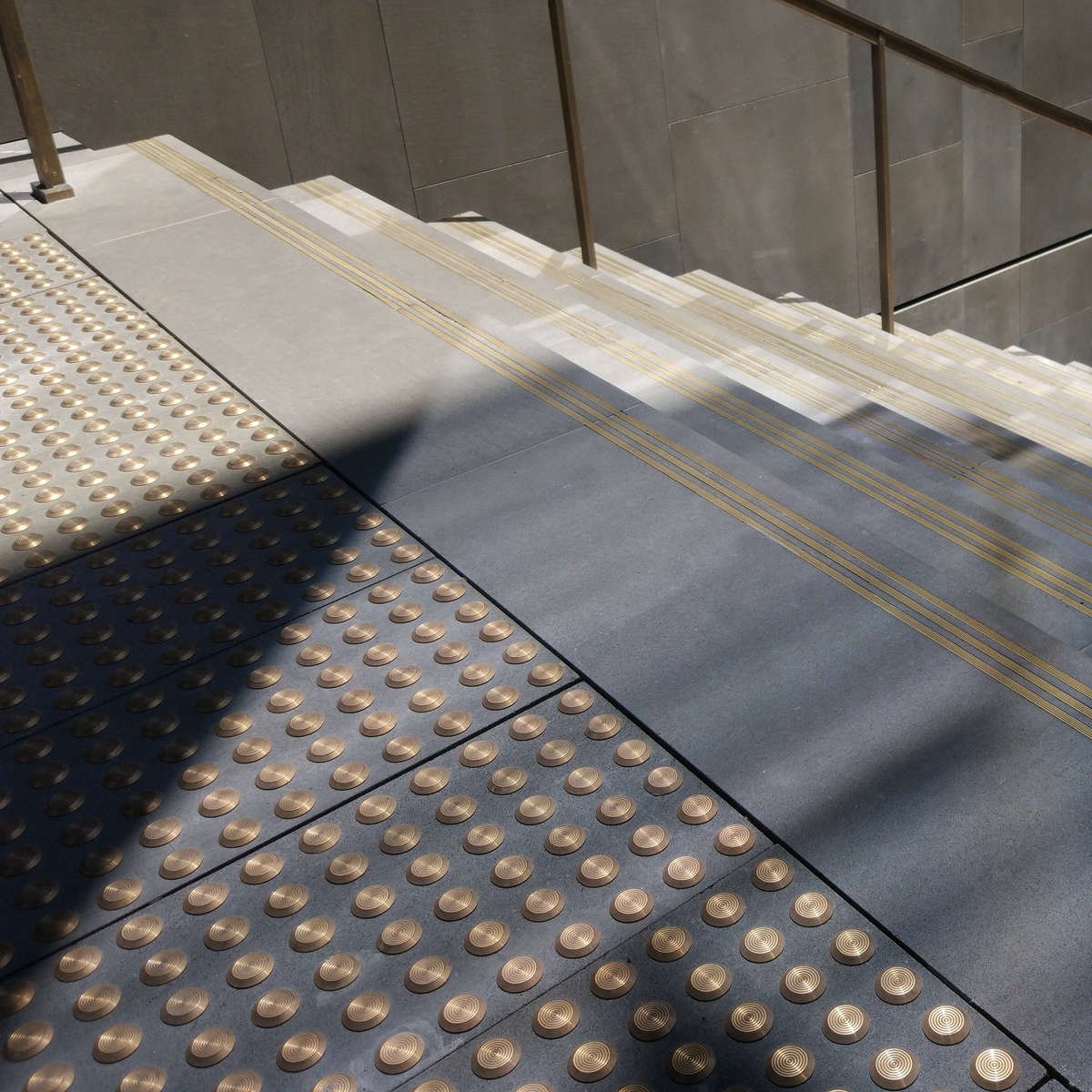 TacPro brass tactile indicators on bluestone tiles at the top of stairs