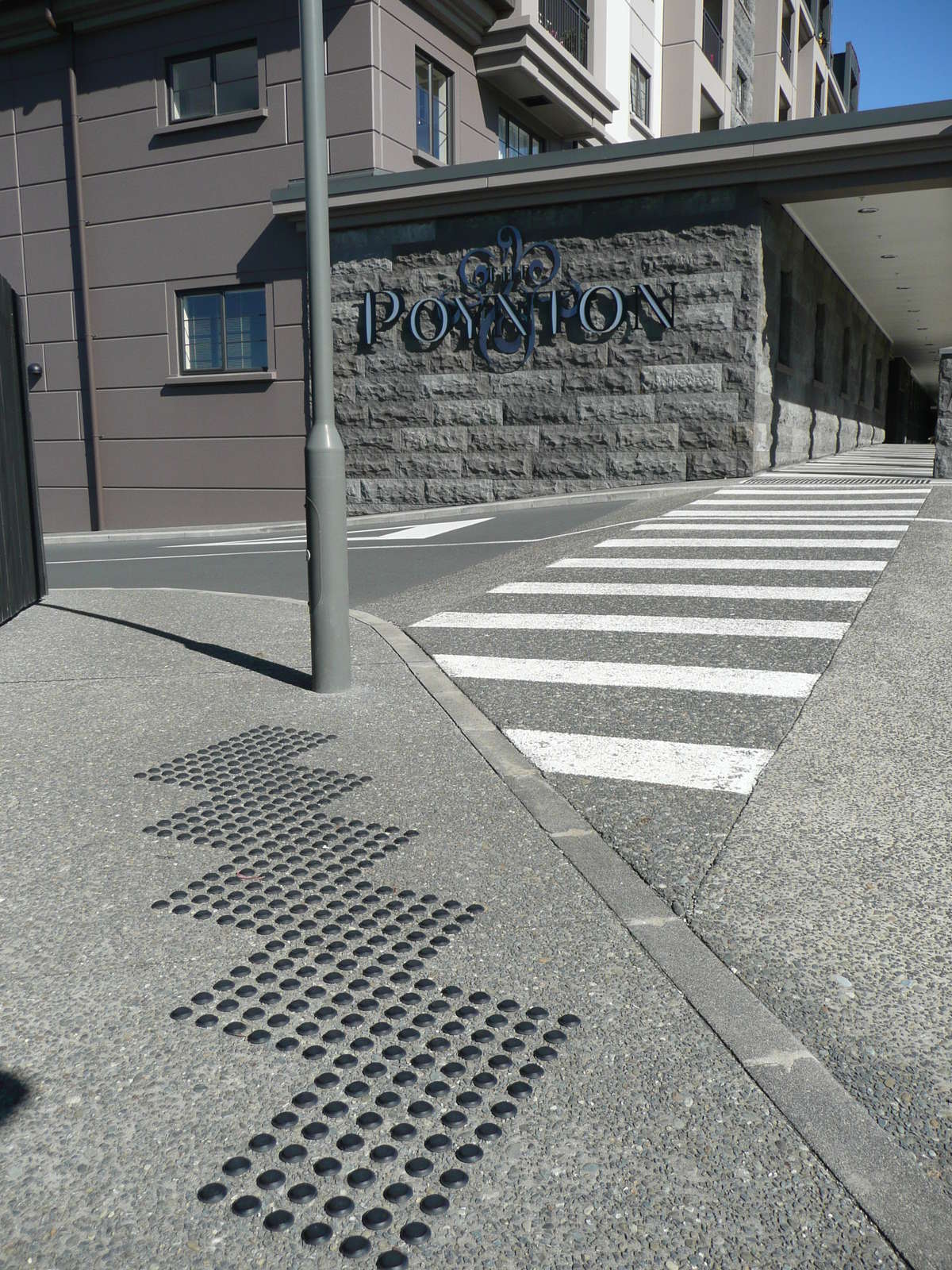 TacPro black polyurethane tactile indicators installed on concrete at zebra crossing outside retirement village