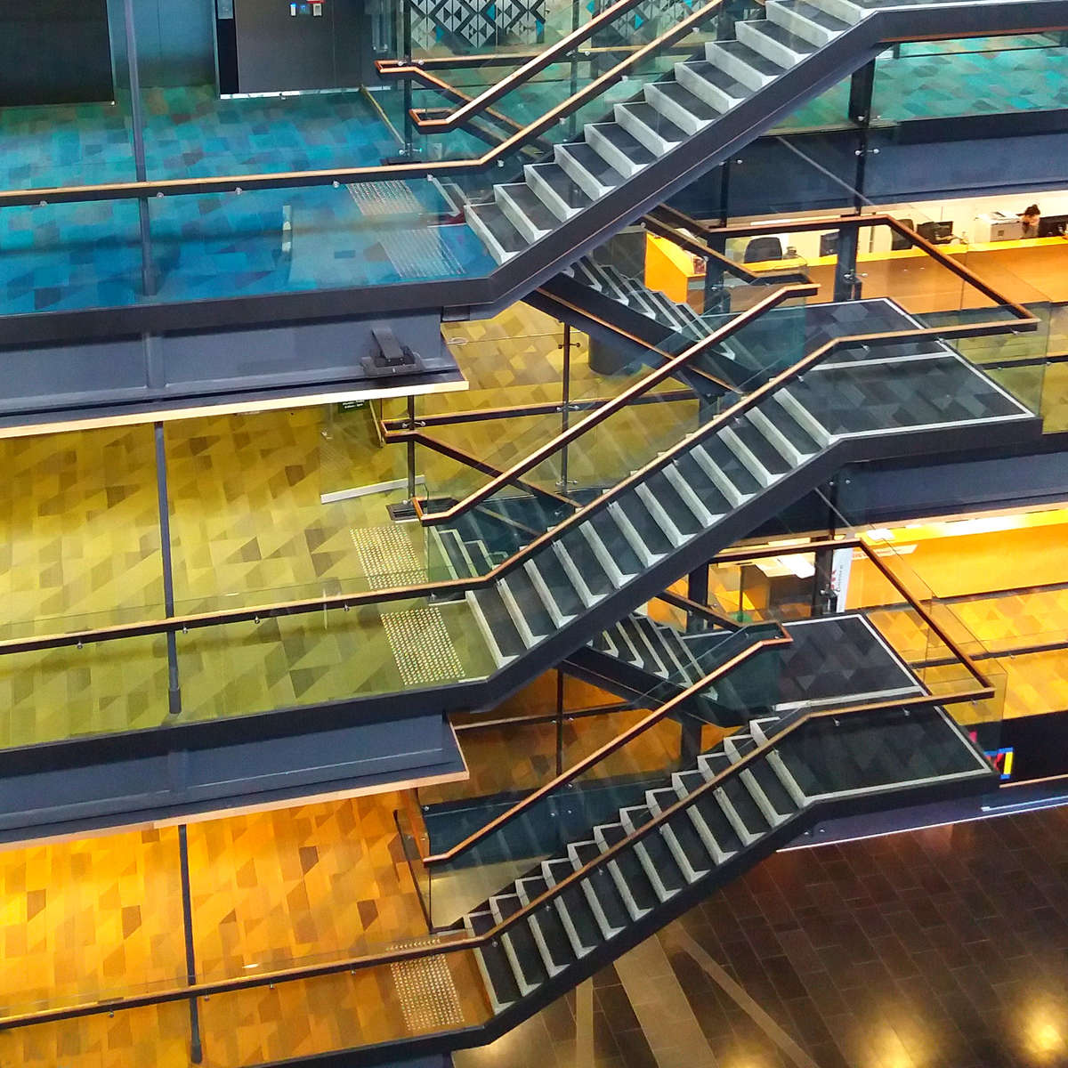 High angle view of TacPro stainless steel tactile indicators installed to carpet on multi-level stair case