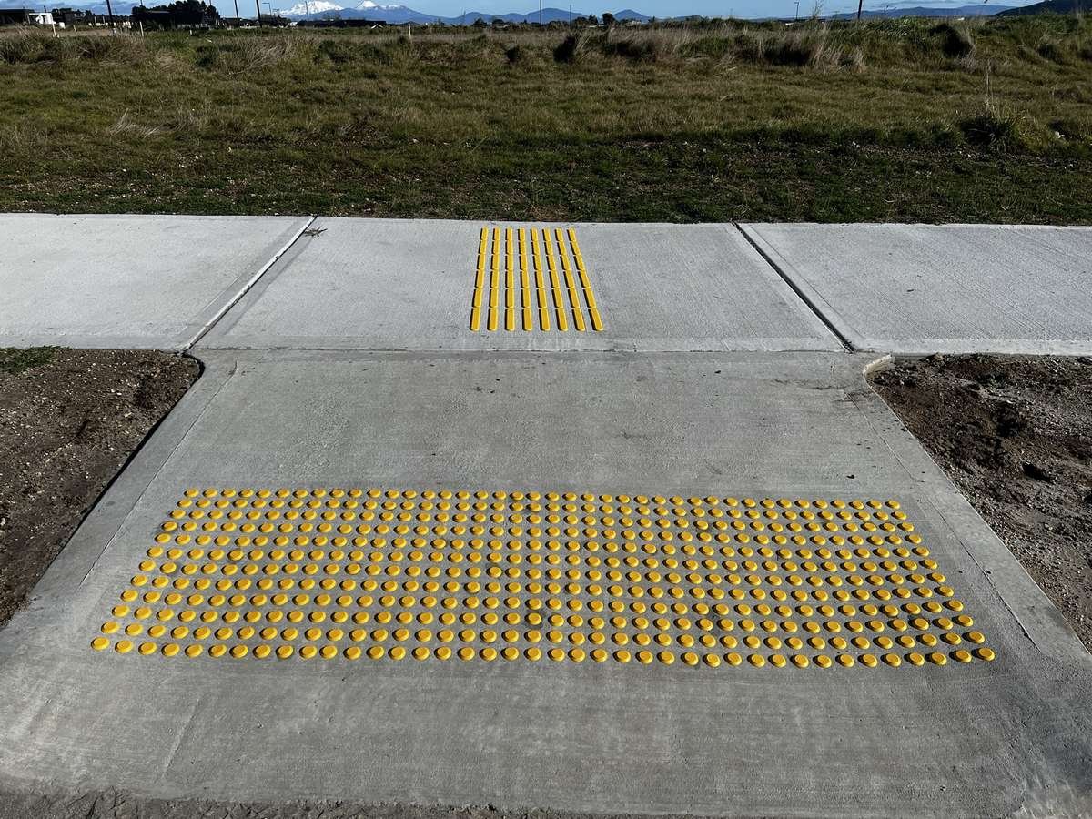 TacPro yellow polyurethane warning and directional tactile indicators on concrete at a new subdivision pram crossing