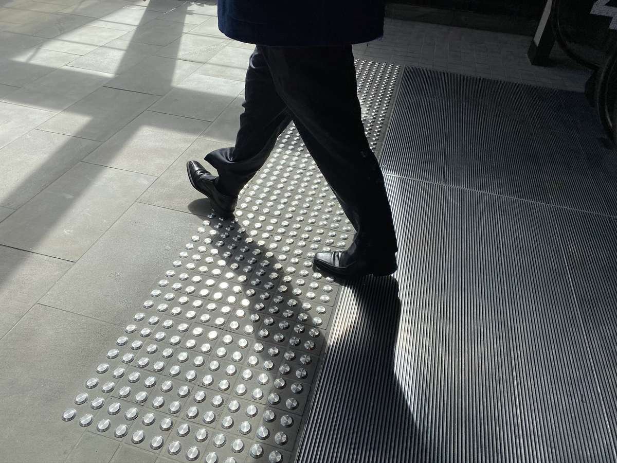 Man walking on TacPro stainless steel tactile indicators at top of escalators