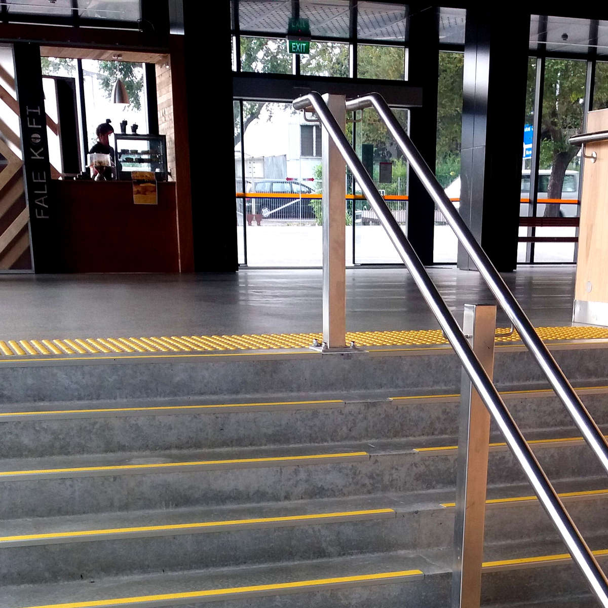 Yellow polyurethane tactile indicators on polished concrete at top of stairs