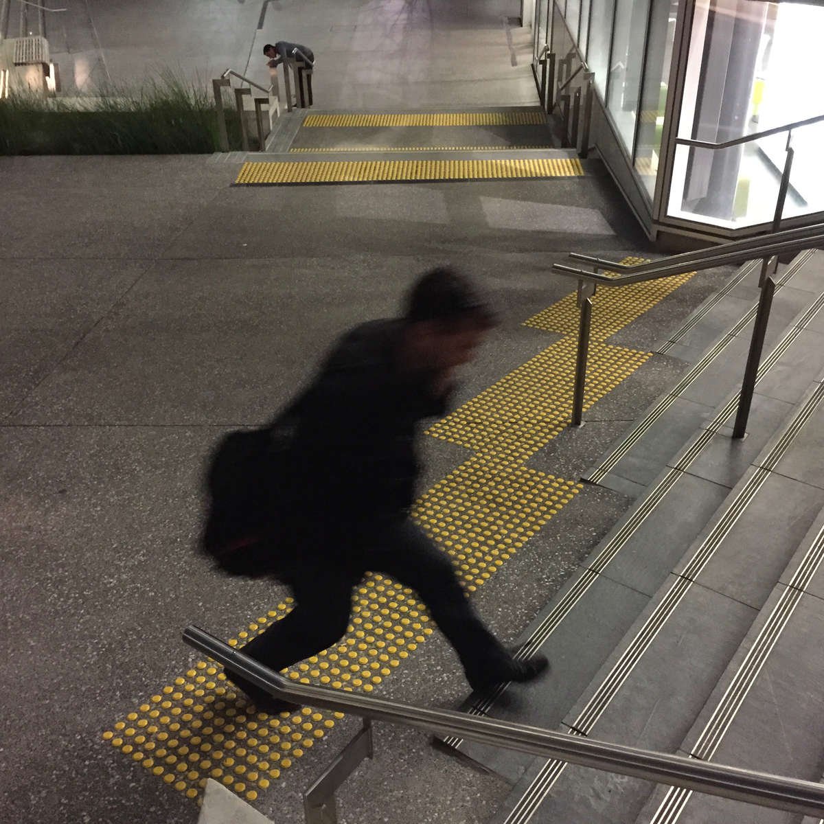 Man walking on TacPro yellow polyurethane tactile indicators at bottom of stair, with other stairs in background