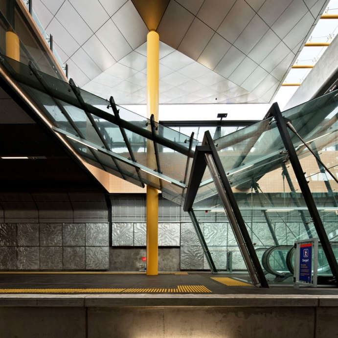 TacPro yellow polyurethane tactile indicators installed on train station platform as viewed by someone on the other side of the tracks