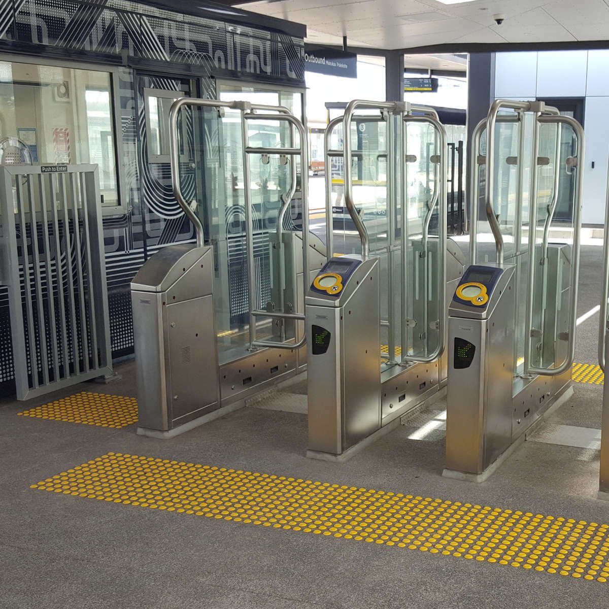 Yellow polyurethane tactile indicators on concrete at train station ticket gates