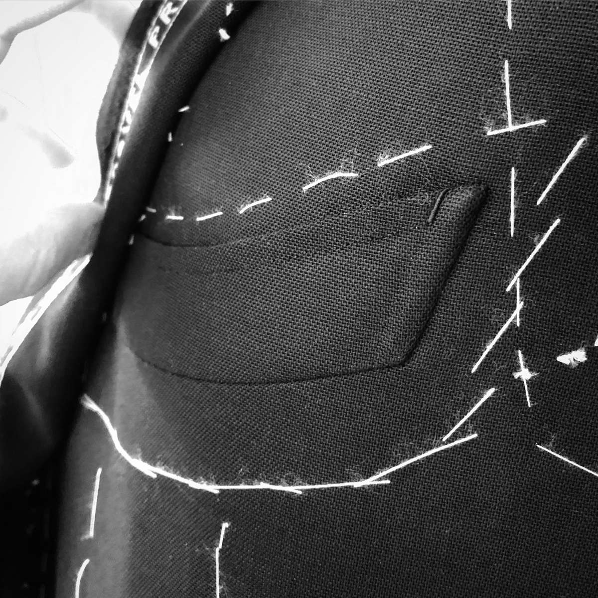 Sartoria Sciarra entirely hand crafted bespoke jacket in progress. Close up of barchetta out breast pocket with hand crafted bar tack and top stitching using Italian silk twist strengthened with bees wax. Made from a bright navy Loro Piana Zelander high twist wool fabric. Luxury bespoke Neapolitan tailoring. 