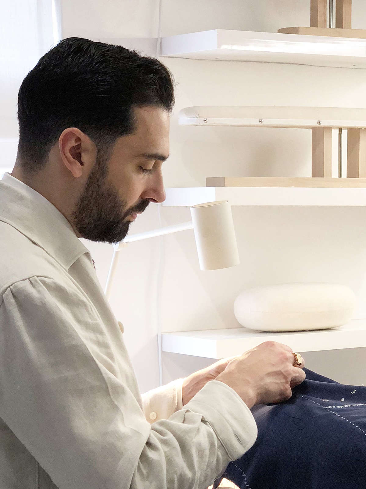 Carl Sciarra director and bespoke tailor at Sartoria Sciarra hand sewing the seams on a bespoke jacket using Italian silk twist strengthened with bees wax. Bespoke suit made from a bright navy Loro Piana Zelander high twist wool fabric. Luxury bespoke Italian tailoring. 