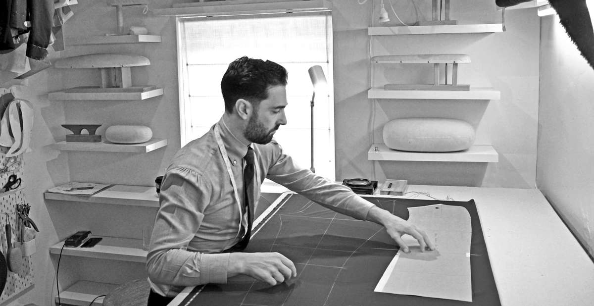 Carl Sciarra director and bespoke tailor at Sartoria Sciarra in the work room chalking a bespoke suit onto Loro Piana Zelander high twist wool. Cotton cashmere bespoke shirt with manica mappina and Italian roll button down collar, shantung silk grenadine tie with a hand rolled tip. Tailors pressing boards and hams, Tailors tool board.