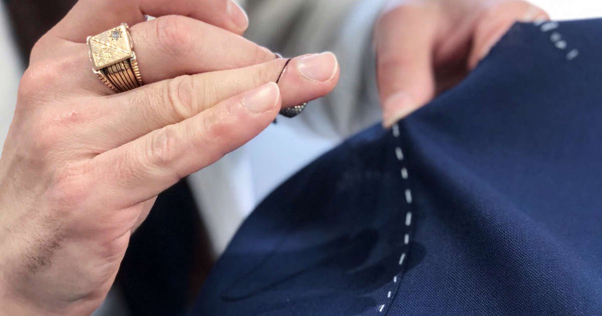 Carl Sciarra director and bespoke tailor at Sartoria Sciarra hand sewing seams with Italian silk thread strengthened with bees wax on a Loro Piana Zelander high twist wool suiting fabric in bright navy. Basted hand stitched. Gold signet ring with rose cut diamond.