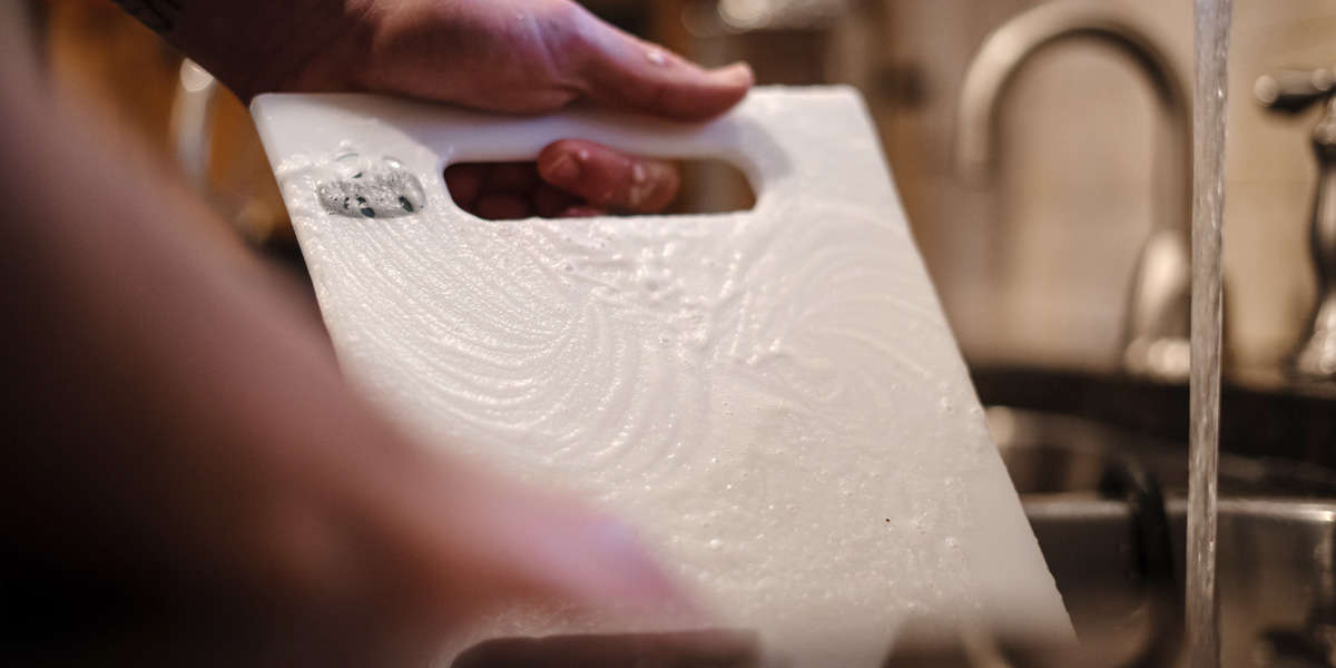 A person scrubbing a cooler divider with dish soap and water.