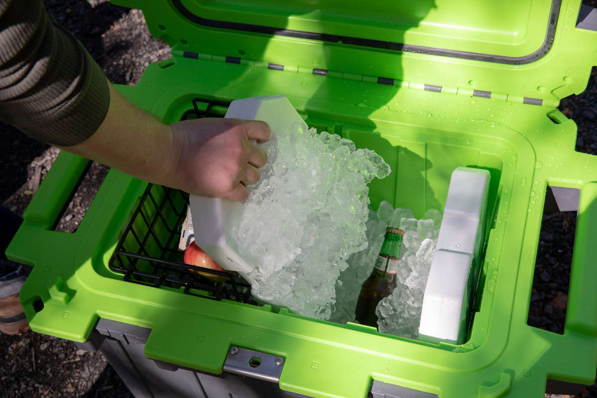 A person pulling a 5lb Pelican Ice pack out of a Pelican Elite Cooler. There is ice frozen all over the reusable ice pack.