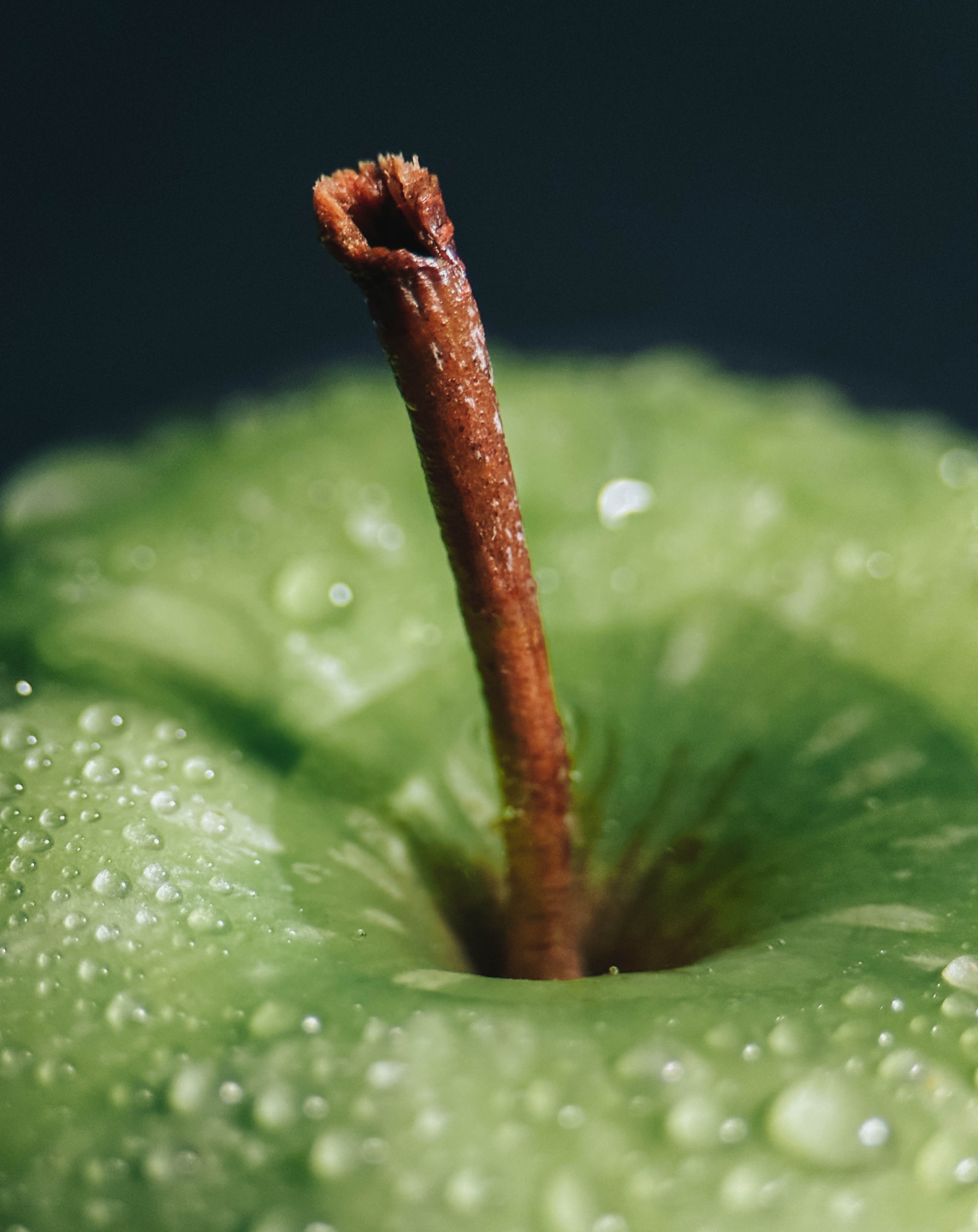 Macro shot on iPhone of a green apple with water droppings. 
