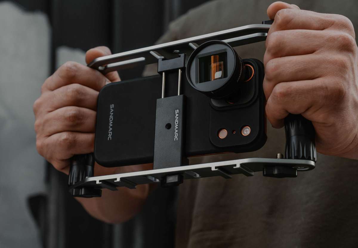 Person standing on rock holding film rig with iPhone attached.