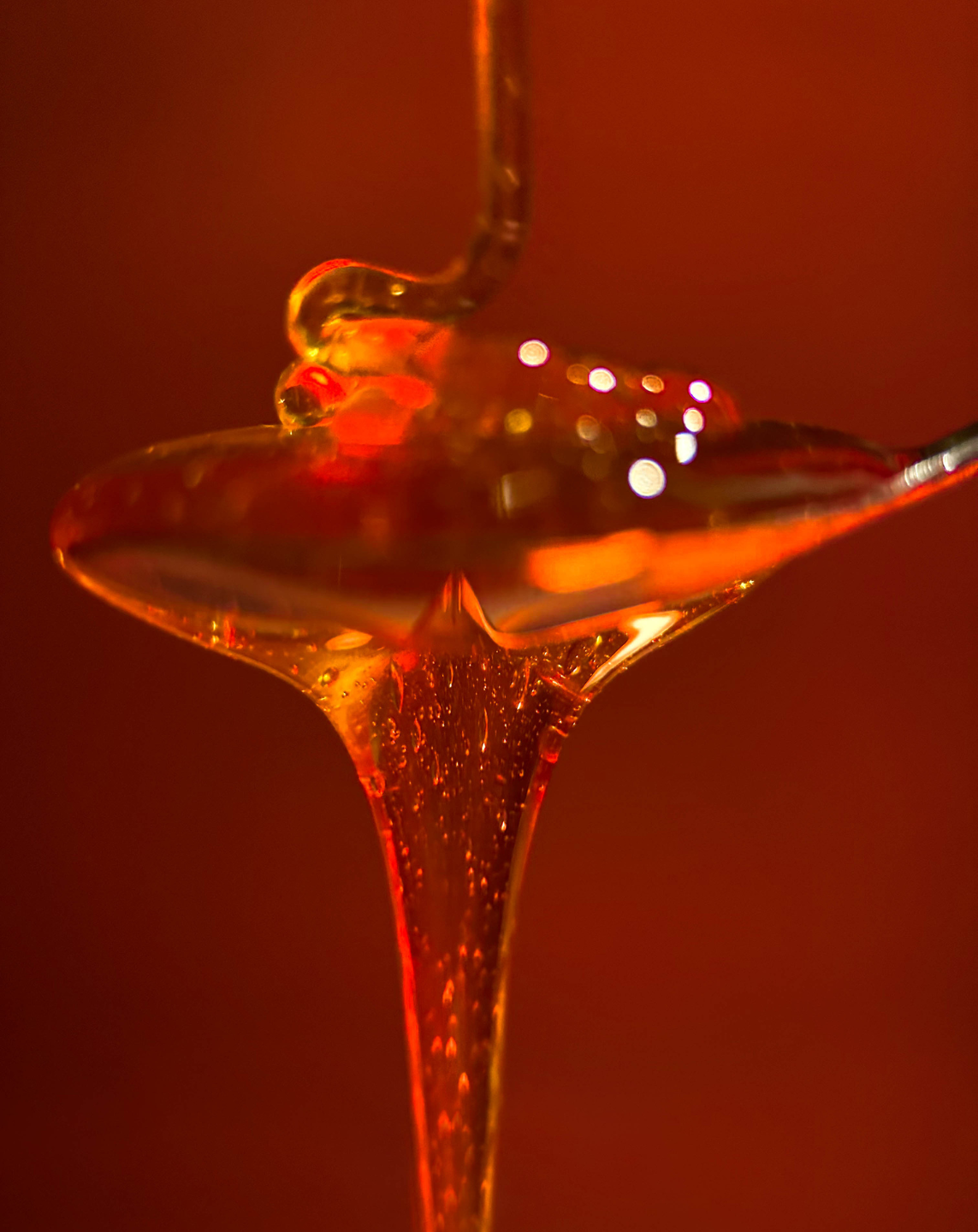 Macro shot on iPhone of honey dripping from a spoon