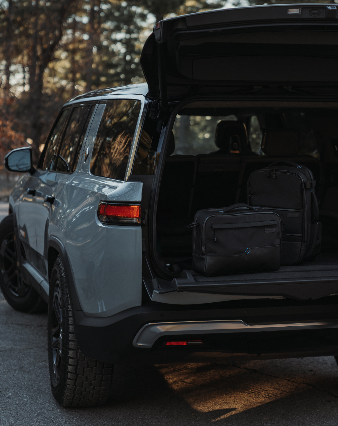 A car with its trunk open and in the backseat are the SANDMARC Travel Backpack and SANDMARC Messenger Pro.