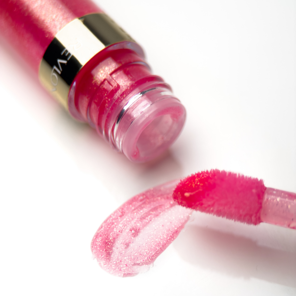 Macro photo of an opened tube of pink Revlon lip gloss with a lip gloss brush on the side.