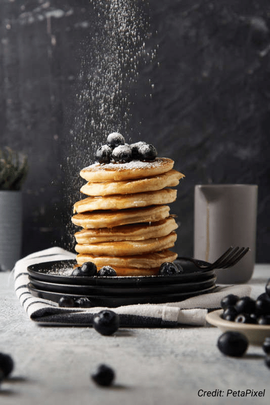 Food photography shot of a stack of pancakes with blueberries and powdered sugar