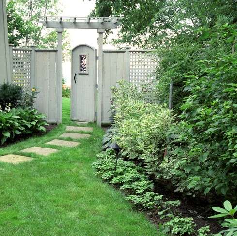 Shade Garden with pathway leading to white fence