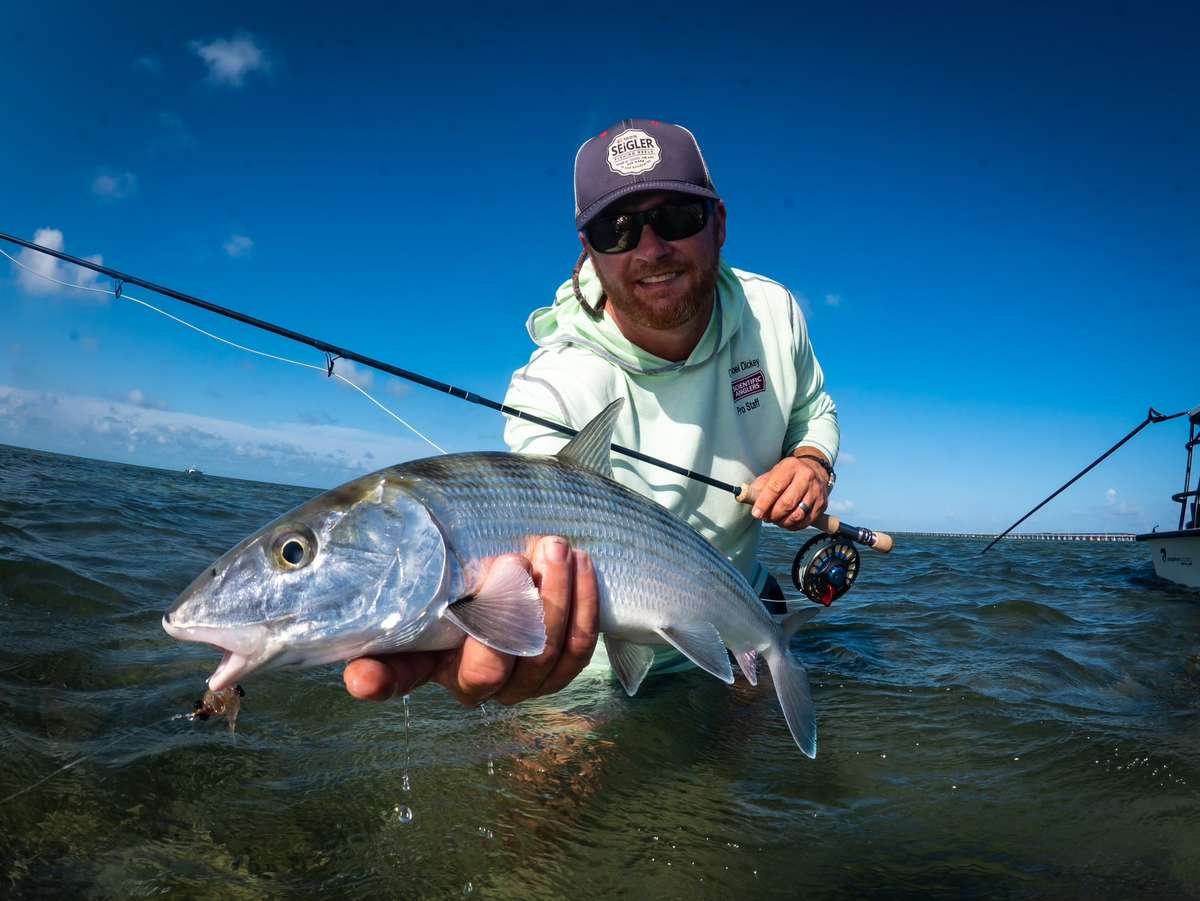 Capt. Joel Dickey, expert Seigler Fly Fishing Guide, skillfully holds a magnificent tarpon by the face on the side of the boat in the breathtaking Florida Keys. Experience the thrill of guided fly fishing adventures with Seigler Fishing Reels