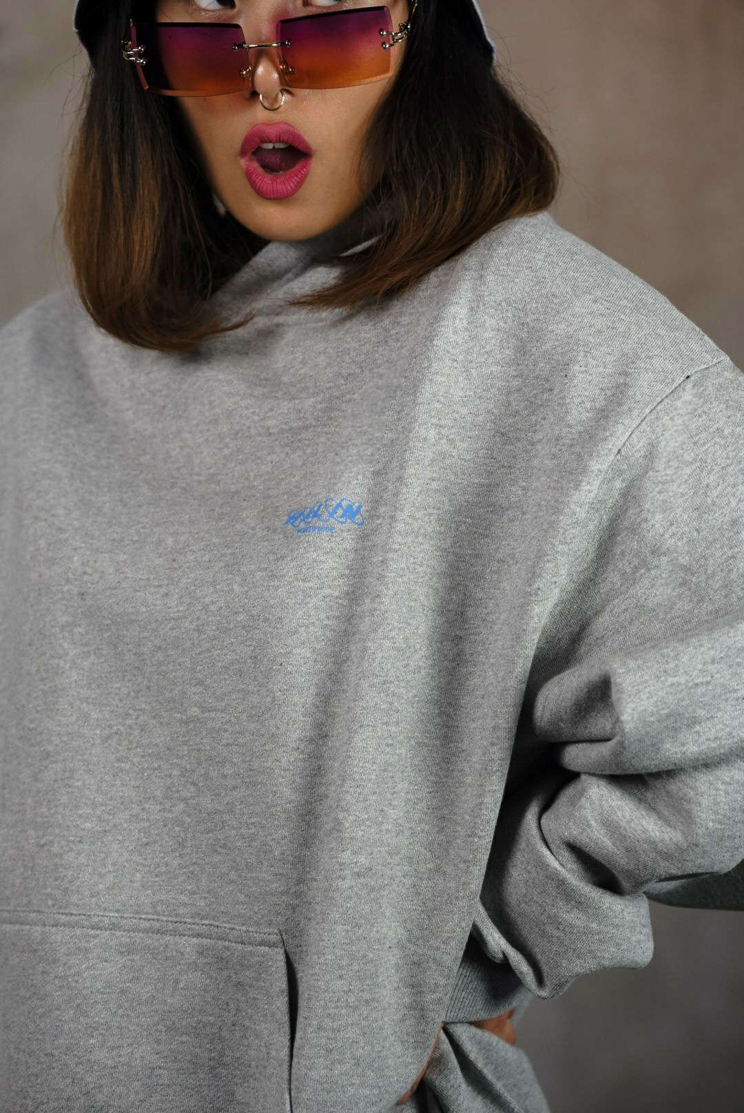 Female streetwear model wearing Halin Bucket Hat and grey oversize hoodie. Female streetwear model wearing Halin Bucket Hat and grey oversize hoodie.