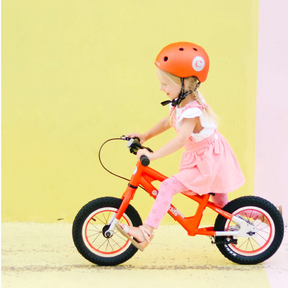 Little girl on an orange balance bike and matching helmet, running Little girl on an orange balance bike and matching helmet, running