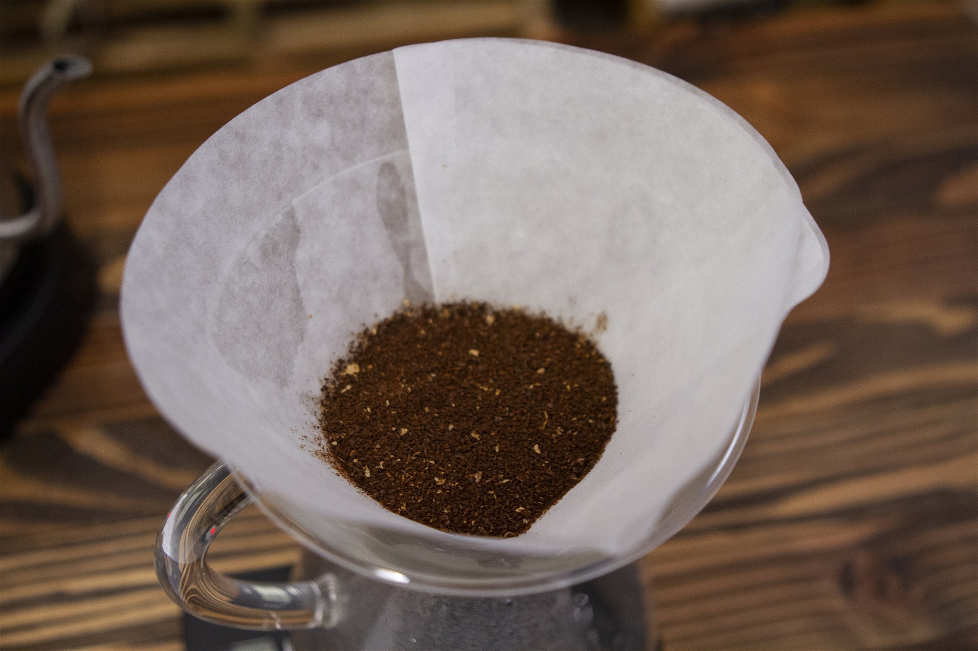 POURING WATER ON TO COFFEE GROUNDS IN CHEMEX