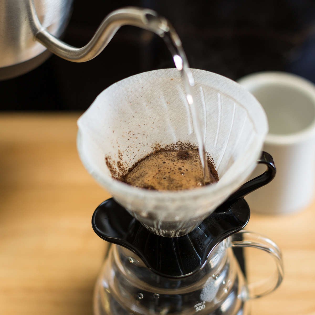 POURING WATER ON TO COFFEE GROUNDS IN V60