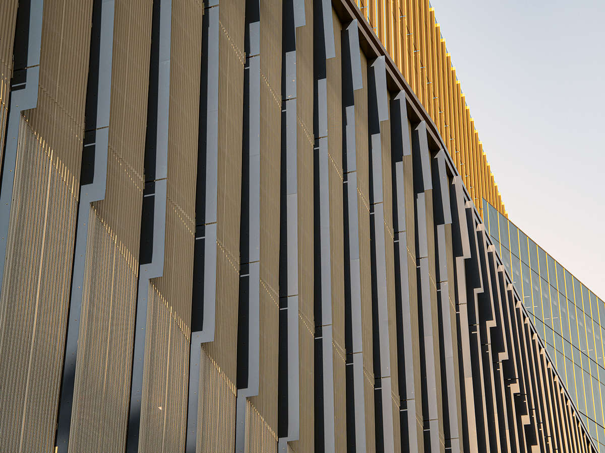 An abstract view of the Siteman Cancer Center, showing the morning sun as it hits a series of vertical openings. The sun's rays catch and reflect a gradient as they move across the building's face.