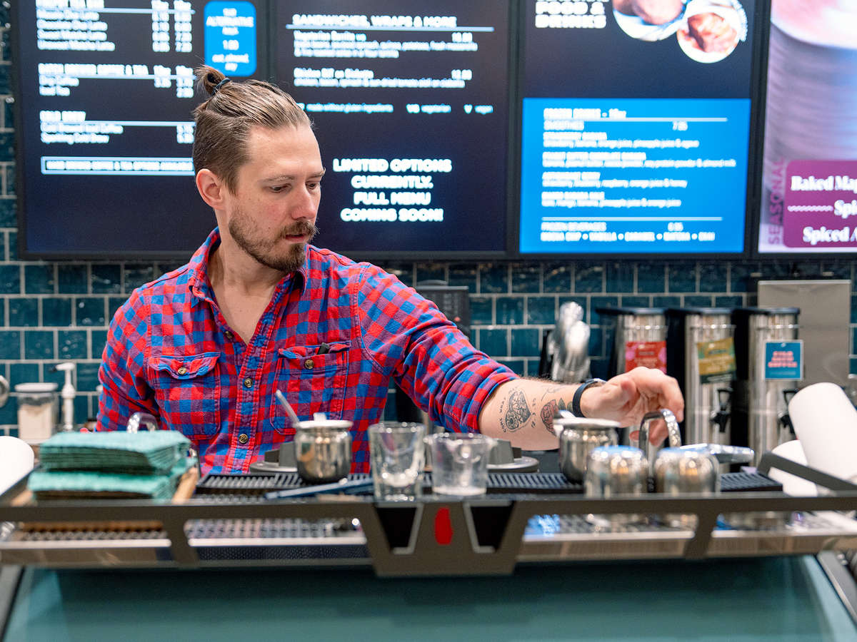 A barista wearing flannel works an espresso machine.