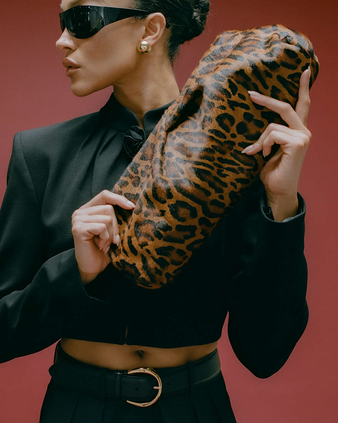 model holding a leopard print calf-hair textured clutch