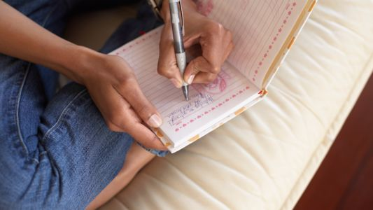Left-handed woman writing journal entry