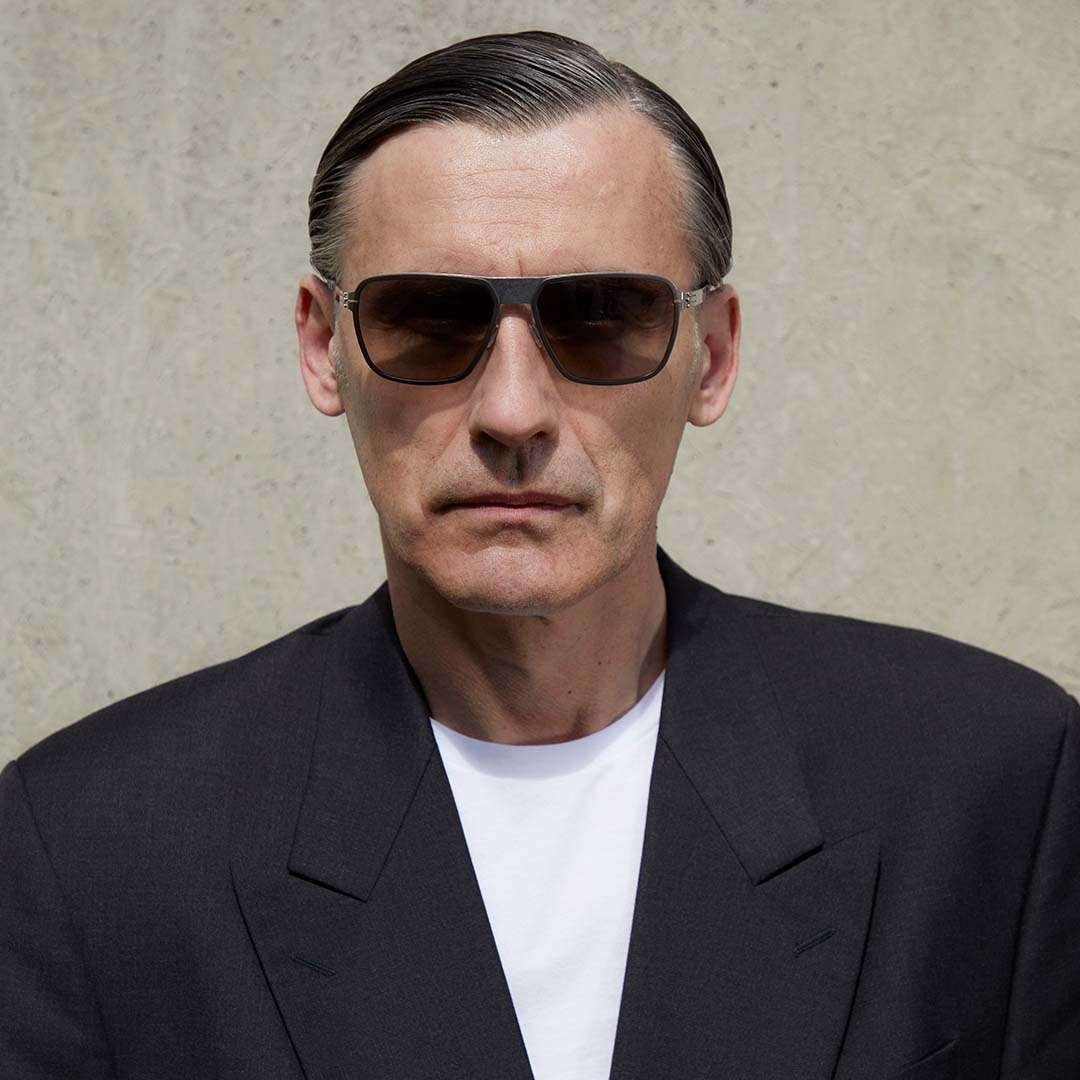 man wearing a suit and bold ic! berlin sunglasses