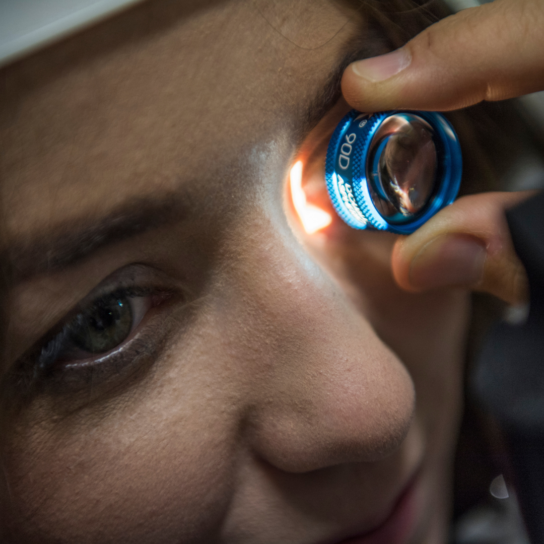 Az optometrista Basic látásvizsgálatot végez, egy lencsét tart a páciens szeme elé.